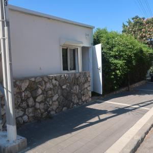 un edificio bianco con un muro in pietra e una finestra di הצימר של תמר - אורחן מתאים לדתיים a Safed