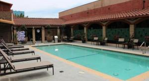 a large swimming pool with chairs and a building at Alhambra Hotel in Alhambra
