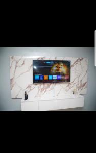 een flatscreen-tv op de top van een witte kast bij Hilltop apartment Ikeja in Agidingbi