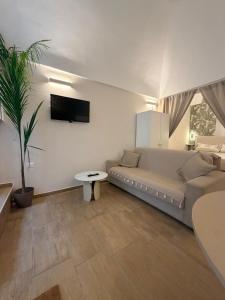 een woonkamer met een bank en een tv aan de muur bij Civico 27 in Ostuni