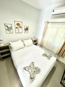 een slaapkamer met een wit bed met bloemen erop bij Yada House s&s in Nai Yang Beach