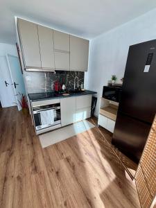 een keuken met witte kasten en een zwarte koelkast bij 2 Bedrooms, Tram, secure residence in Bron