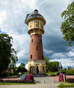 a lighthouse in a park with a car parked next to it at Hotelik Gołdap in Gołdap