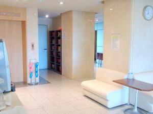 a waiting room with a white couch and a clock at Okaya Central Hotel in Okaya