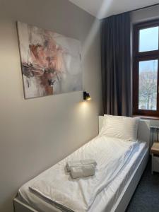 a bedroom with a white bed with a painting on the wall at Wielkopolanka Pokoje gościnne i Restauracja in Chodzież