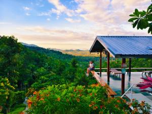 a man sitting on a wooden platform overlooking a valley at SZ Samui Glamping in Ban Sa Ket