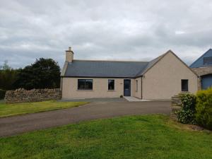 a white house with a driveway in front of it at Auld Hoose in Kirkwall
