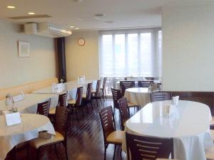 a dining room with white tables and chairs at Okaya Central Hotel in Okaya