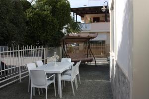 einen weißen Tisch und Stühle sowie einen Regenschirm auf einer Terrasse in der Unterkunft Villetta Angela in Torre San Giovanni Ugento