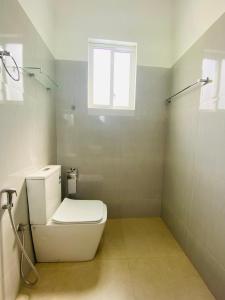 a white bathroom with a toilet and a window at Lavish in Weligama