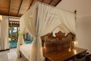 a bedroom with a canopy bed and a wooden desk at Oruva Beachside Villa in Galle
