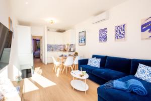 Una sala de estar con un sofá azul y una mesa. en Infinity Blue - Sunny Coastal Apartment, en Ospedaletti