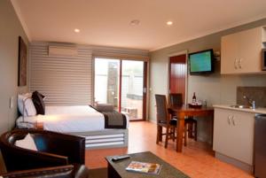 a hotel room with a bed and a table and a kitchen at Bairnsdale Motel in Bairnsdale