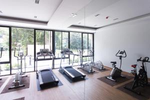 a gym with several treadmills and elliptical machines at The Journey Hotel Laksi in Bangkok