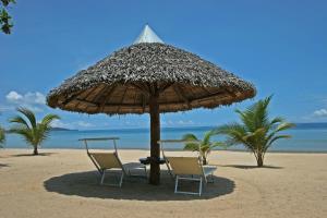 two chairs and an umbrella on the beach at Eden Lodge in Madirokely