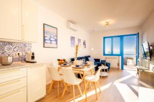 Una cocina y una sala de estar con mesa y sillas. en Infinity Blue - Sunny Coastal Apartment, en Ospedaletti