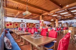 een restaurant met houten plafonds en tafels en rode stoelen bij Das Arber-Hotel am Rothbach in Bodenmais