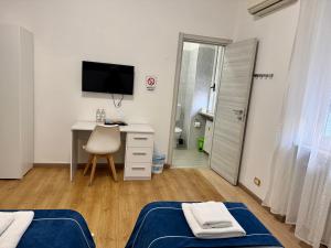 een slaapkamer met 2 bedden, een bureau en een televisie bij Nuovo Confortini Rooms SUNDAY in Verona