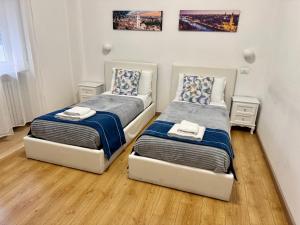 2 aparte bedden in een kamer met houten vloeren bij Nuovo Confortini Rooms SUNDAY in Verona