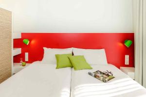 ein Schlafzimmer mit einem weißen Bett mit rotem Kopfteil in der Unterkunft ibis Styles Karlsruhe Ettlingen in Ettlingen