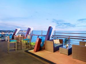 a balcony with chairs and tables on a roof at The Kuta Beach Heritage Hotel - Managed by Accor in Kuta