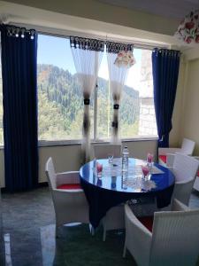 ein Esszimmer mit Tisch und Stühlen und einem großen Fenster in der Unterkunft Copacabana Hotel & restaurant in Nathia Gali