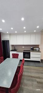 a kitchen with a table and white cabinets and red chairs at Apartmani MURIC Ljubljana in Ljubljana