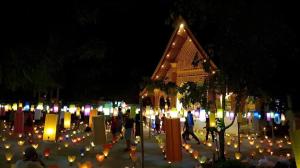 Un grupo de personas caminando por un cementerio por la noche. en The View Pavilion Hotel, en Luang Prabang