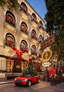 een rode auto geparkeerd voor een gebouw met een kerstboom bij 龄舍1927酒店 in Wuhan