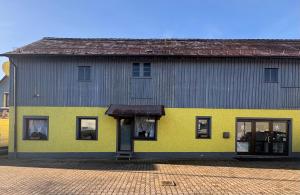 um edifício amarelo e cinzento com uma porta em MPK Motorsport Apartment em Waldsassen