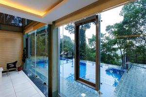 een glazen huis met uitzicht op een zwembad bij Stallion Estates in Munnar +42 foto's