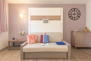 a couch in a room with a clock on the wall at Résidence Pierre & Vacances La Promenade des Bains in Saint-Raphaël