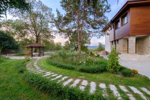 a garden next to a building with a gazebo at Guesthouse Gostilitsa in Gostilitsa