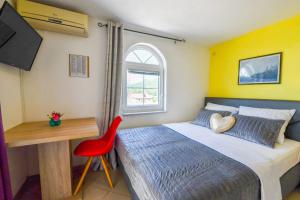 una camera con letto, scrivania e sedia rossa di Villa Lilly 2 a Cesarica