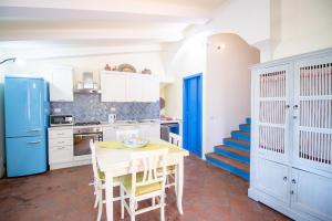 a kitchen with a table and a blue refrigerator at S'Omu e Assunta in Cardedu