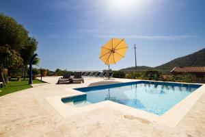 a swimming pool with a yellow umbrella and chairs at S'Omu e Assunta in Cardedu