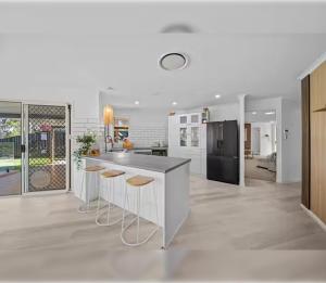 La cuisine est équipée d'un comptoir avec tabourets et d'un réfrigérateur. dans l'établissement 4BR Coomera Views! Prime Gold Coast Near Beaches, à Gold Coast