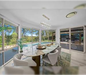 une salle à manger avec une table, des chaises et des fenêtres dans l'établissement 4BR Coomera Views! Prime Gold Coast Near Beaches, à Gold Coast