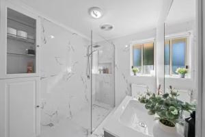 une salle de bain blanche avec une douche et un lavabo dans l'établissement 4BR Coomera Views! Prime Gold Coast Near Beaches, à Gold Coast