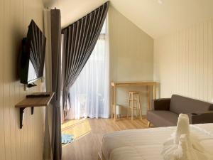 a bedroom with a bed and a couch and a window at Miramalin Resort Krabi in Ao Nang Beach