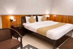 een slaapkamer met een groot bed en een stoel bij IVY The Boutique Hotel By Backpacker Stop in Nainital