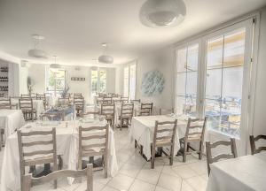 a dining room with white tables and chairs and windows at Il Lido in Giannella