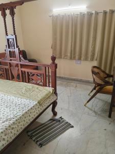a bedroom with a bed and a chair and a window at Chaps le guest house in Patna