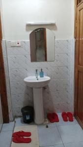 ein Bad mit einem Waschbecken, einem Spiegel und roten Hausschuhen in der Unterkunft Serene Stays in Naivasha