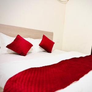 eine rote Decke auf einem weißen Bett mit roten Kissen in der Unterkunft Hotel Stay Inn in Sohāna
