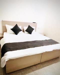 ein großes Bett mit schwarzen und weißen Kissen darauf in der Unterkunft Hotel Stay Inn in Sohāna