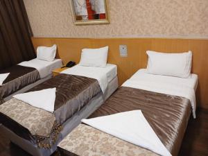 una stanza con tre letti in una stanza di فندق رمال الخليج a Quai