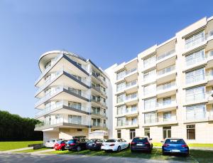 a large apartment building with cars parked in a parking lot at Diune Resort by Zdrojowa in Kołobrzeg