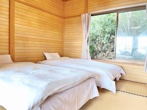 two beds in a room with a window at Balistyle Tateyama View in Tateyama