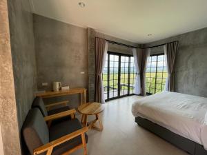 a bedroom with a bed and a chair and a window at Por Sampao Camp&Resort in Ban Pha Saeng Lang